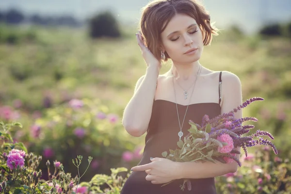 Schöne junge Frau in einem blühenden Rosengarten — Stockfoto