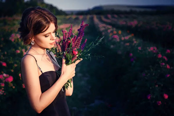 Vacker ung kvinna i en blommande rosenträdgården — Stockfoto