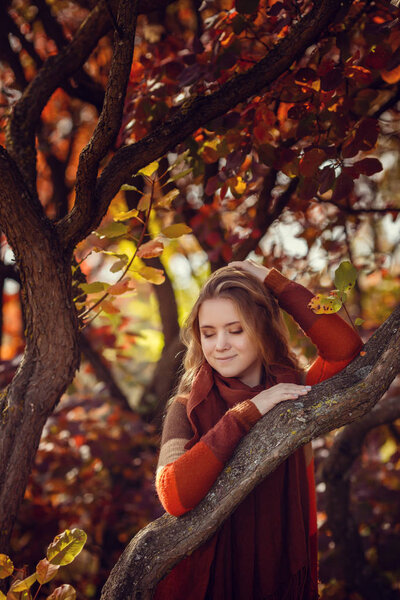 Portrait of beautiful girl walking the park. Smiling. Warm sunny weather. Outdoors. Red, orange and yellow