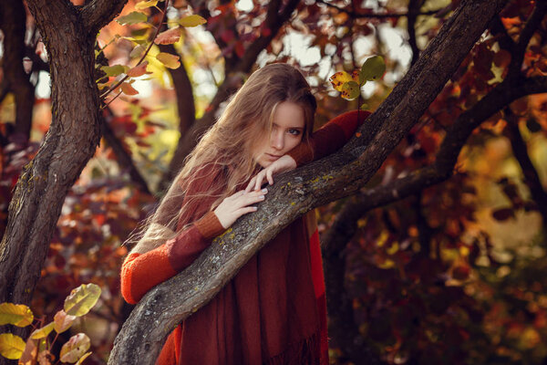 Portrait of beautiful girl walking the park. Smiling. Warm sunny weather. Outdoors. Red, orange and yellow