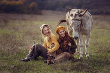 İki çekici genç kadın doğa ile birlikte bir şirin eşek üzerinde tutun.