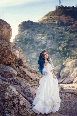 Cliff'in kenarında duran ve geniş Deniz Manzaralı arıyorum genç kadın. Rüzgar uzun mavi saç.