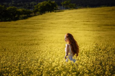 Sarı bir alan içinde kırmızı saçlı genç kız. Bahar ve özgürlük