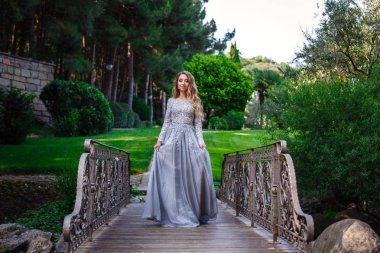 Lüks payetler elbise ve gümüş aksesuarlar sarı saçlı zarif güzel kadın moda açık fotoğraf, yaz parkında poz