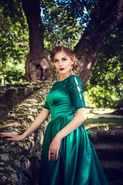 Mujer joven con un vestido verde explora un bosque mágico —  Fotos de Stock