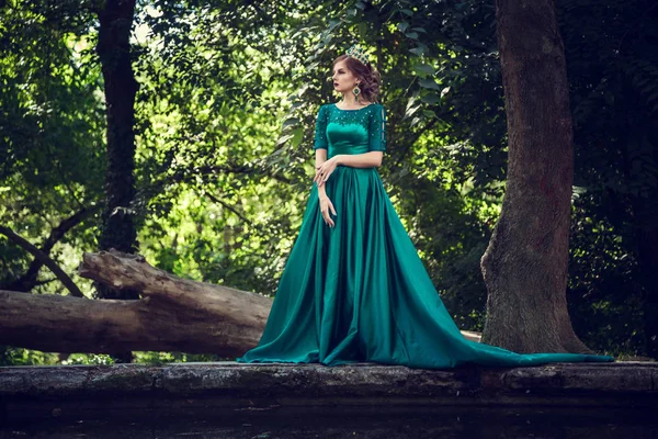 Mujer joven con un vestido verde explora un bosque mágico —  Fotos de Stock