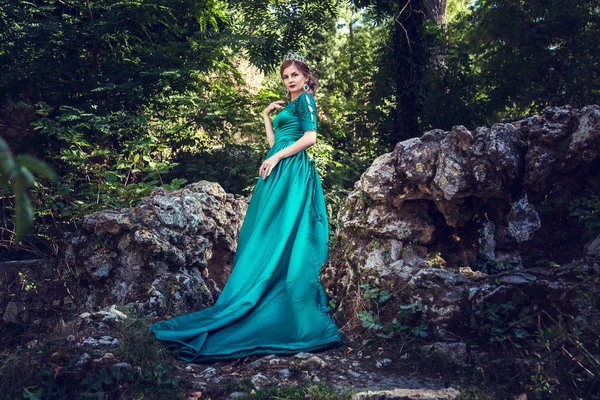 Jovem usando um vestido verde explora uma floresta mágica — Fotografia de Stock