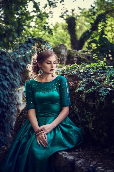 Молода жінка в зеленому платті досліджує чарівний ліс — стокове фото