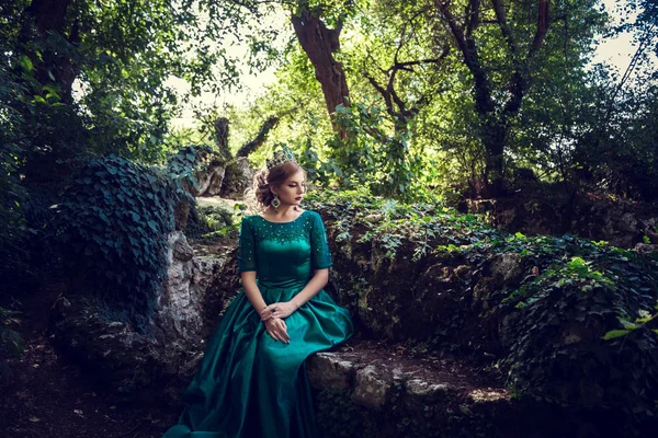 Jovem usando um vestido verde explora uma floresta mágica — Fotografia de Stock