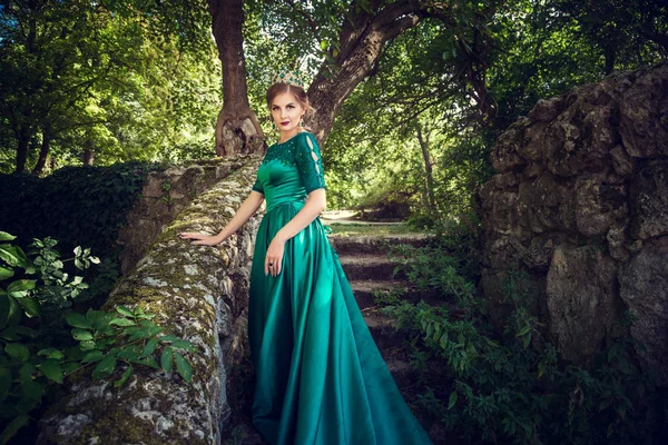 Mujer joven con un vestido verde explora un bosque mágico — Foto de Stock
