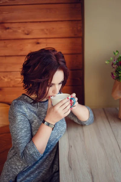 Linda mujer bebiendo café en taza blanca en café en la ciudad. Caída ca — Foto de Stock