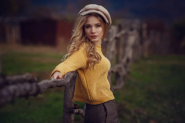 A girl with blond hair in fashionable clothes in the style of Provence and a cap enjoys the fresh air of the countryside — Stock Photo, Image