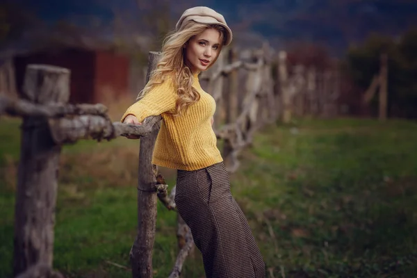 A girl with blond hair in fashionable clothes in the style of Provence and a cap enjoys the fresh air of the countryside — Stock Photo, Image