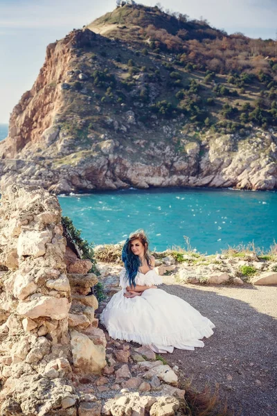Giovane donna in piedi sul bordo della scogliera e guardando in un'ampia vista sul mare. Vento Lungo Capelli blu acconciatura . — Foto Stock