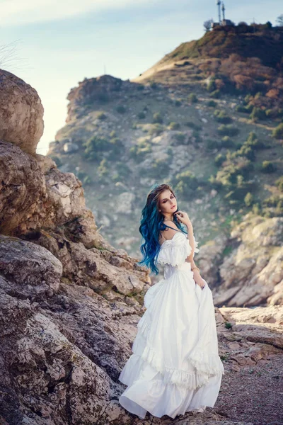 Cliff'in kenarında duran ve geniş Deniz Manzaralı arıyorum genç kadın. Rüzgar uzun mavi saç.