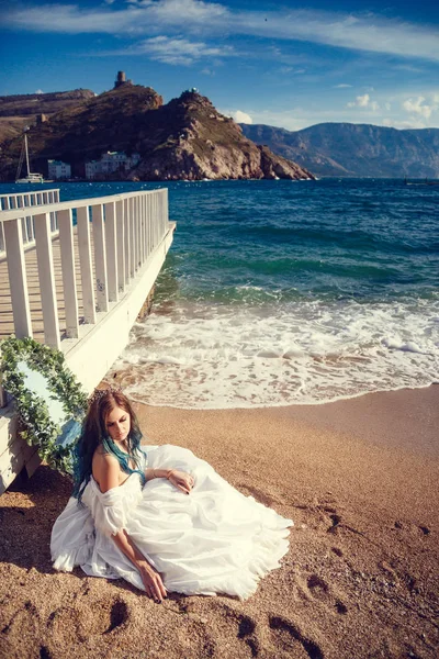 Bella ragazza con i capelli blu e in un abito bianco vintage guarda il mare. Nelle sue mani un bellissimo specchio antico, in cui il mare si riflette. Copertina libro — Foto Stock