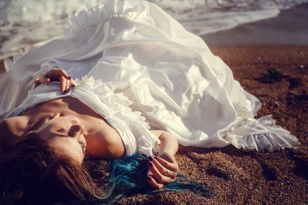 Красивая девушка с голубыми волосами и в белом винтажном платье смотрит на море. В ее руках красивое старинное зеркало, в котором отражается море. Обложка книги — стоковое фото