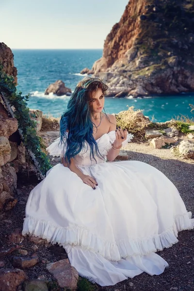 Cliff'in kenarında duran ve geniş Deniz Manzaralı arıyorum genç kadın. Rüzgar uzun mavi saç.