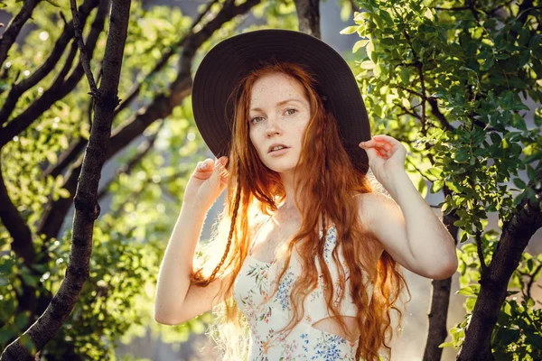 Hermosa joven pelirroja bajo la sombra de un árbol verde — Foto de Stock