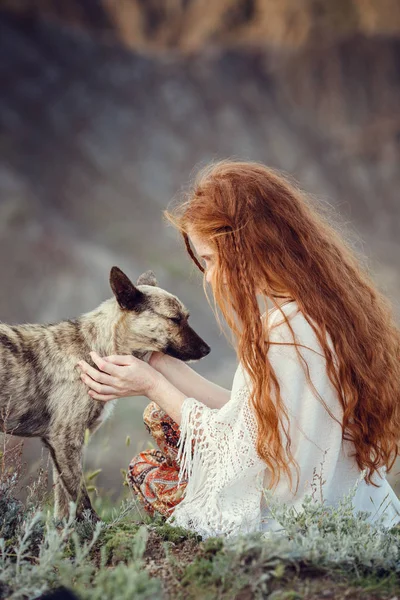 一个年轻的女孩, 一个博霍风格的女孩, 带着她的狗在海岸上。自由和嬉皮士的理念和概念 — 图库照片