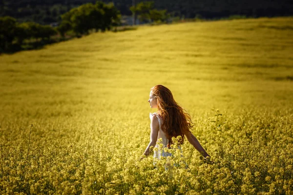 Sarı bir alan içinde kırmızı saçlı genç kız. Bahar ve özgürlük
