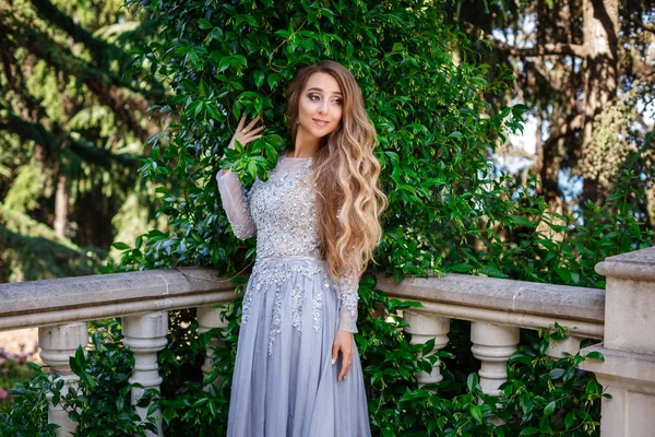 Мода открытая фотография элегантной красивой женщины с светлыми волосами в роскошных блестках платье и серебряные аксессуары, позируя в летнем парке — стоковое фото