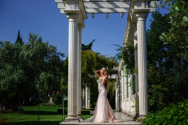 Модна зовнішня фотографія елегантної красивої жінки з світлим волоссям в розкішній сукні з блискітками та срібними аксесуарами, що пропонують в літньому парку — стокове фото