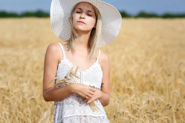 Vacker ung kvinna i vit klänning i ett område av mogna vete. Romantisk stämning på sensommaren. — Stockfoto