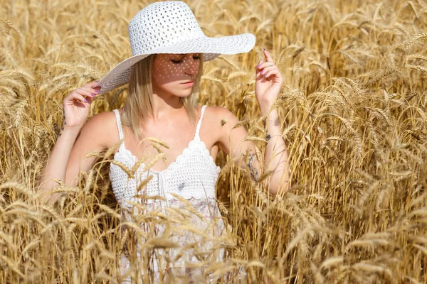Krásná mladá žena v bílých šatech na poli zralé pšenice. Romantická nálada pozdního léta. — Stock fotografie