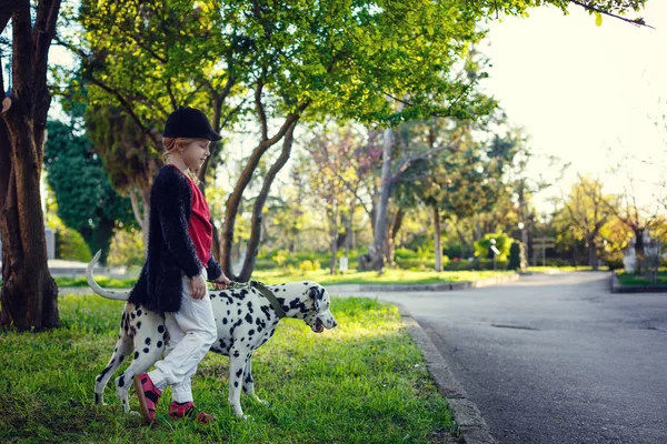 Young girl with her Dalmatian dogs in a spring park
