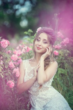 Çiçek parkında güzel bir kadın, bahçe gülleri. Makyaj, saç, gül çelengi.