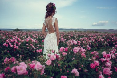 Çiçek parkında güzel bir kadın, bahçe gülleri. Makyaj, saç, gül çelengi.