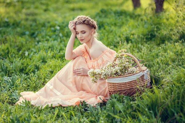 Mooi jong meisje in een oude jurk in een peer-bloeiende tuin. — Stockfoto