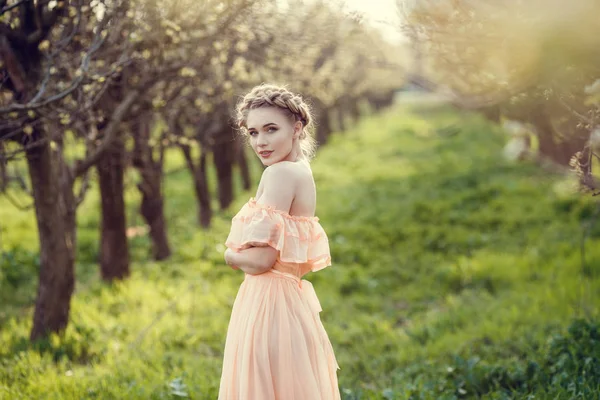 Beautiful young girl in an old dress in a pear-blossoming garden. — Stock Photo, Image