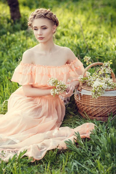 Mooi jong meisje in een oude jurk in een peer-bloeiende tuin. — Stockfoto