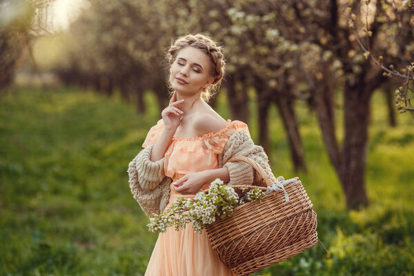 Beautiful young girl in an old dress in a pear-blossoming garden.