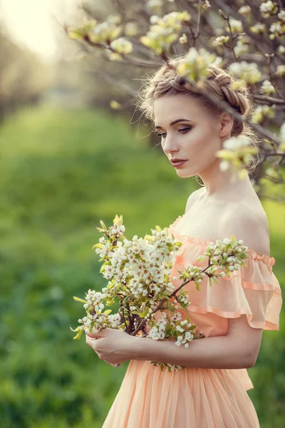 Krásná mladá dívka ve starém obleku v zahradě z hruškovitého květu. — Stock fotografie