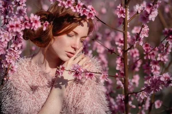 Mooi meisje met rode haren in een zachte perzik Tuin, die bloeide. — Stockfoto