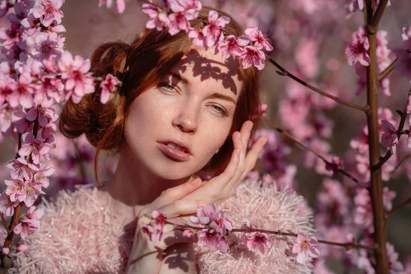 Beautiful young girl with red hair in a gentle peach garden, which blossomed. — Stock Photo, Image