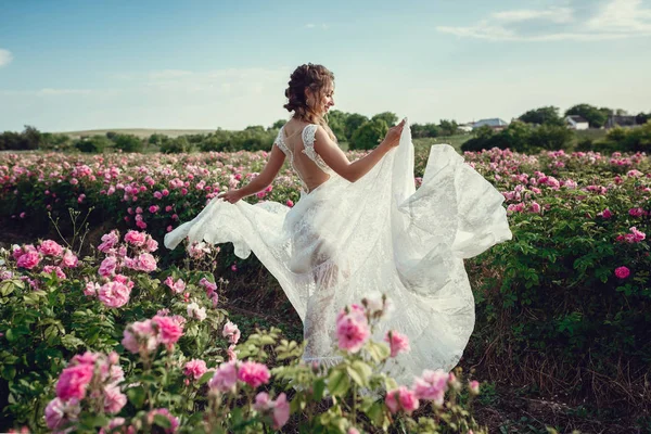 Bella donna in un parco floreale, rose da giardino. Trucco, capelli, una corona di rose . — Foto Stock