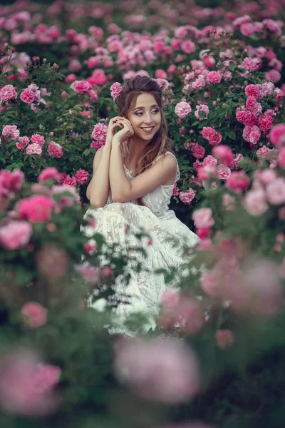 Красива жінка в квітковому парку, садові троянди. Макіяж, волосся, вінок з троянд . — стокове фото