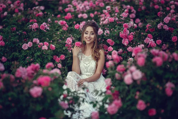 Piękna kobieta w kwiatowym parku, róże ogrodowe. Makijaż, włosy, wieniec róż. — Zdjęcie stockowe