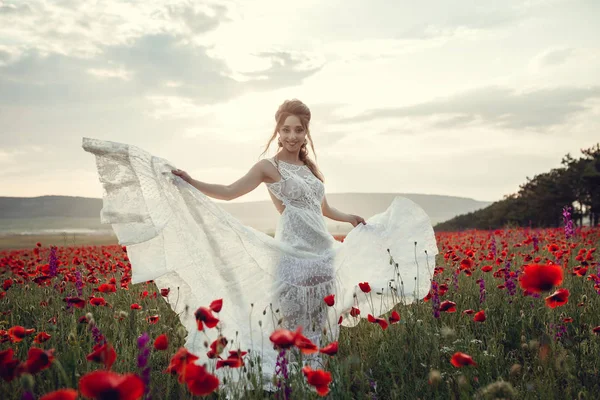 Donna di bellezza nel campo di papavero in abito bianco — Foto Stock