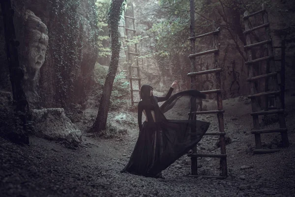 Een mooie vrouw met bleke huid in een zwarte jurk en de zwarte crownk. Gothic look. Outfit voor halloween. — Stockfoto