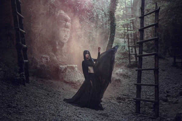 Uma mulher bonita com a pele pálida em um vestido preto e na coroa preta. Olhar gótico. Roupa para halloween . — Fotografia de Stock
