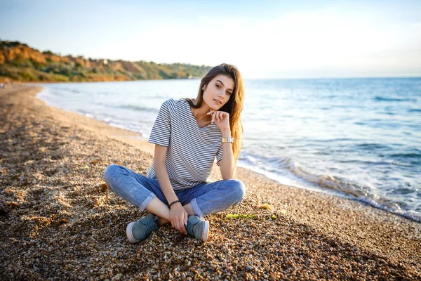 Joven hermosa chica bonita sentada en la playa de arena . — Foto de Stock
