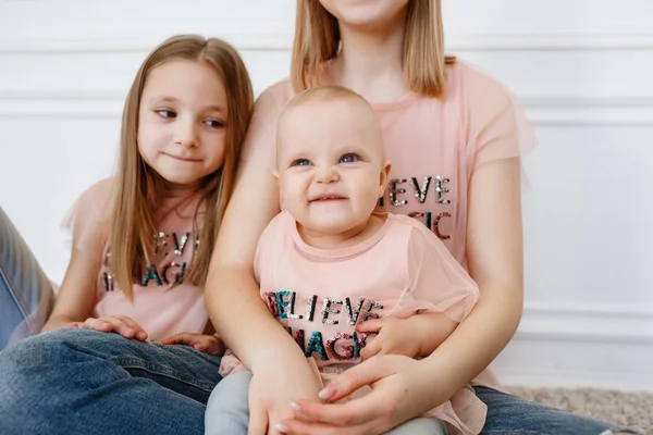 Lehké rodinný seriál. Tři sestry na bílém pozadí, oblečený v funny trička a džíny — Stock fotografie