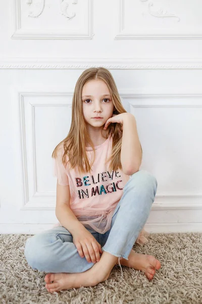 Cute pre-teen girl wearing fashion clothes posing in white interior