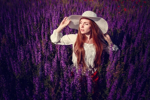 紫色の背景に美しい女性。紫の花を持つ女性 — ストック写真