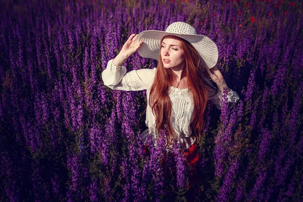 Hermosa mujer sobre fondo púrpura. mujer con flores púrpuras — Foto de Stock